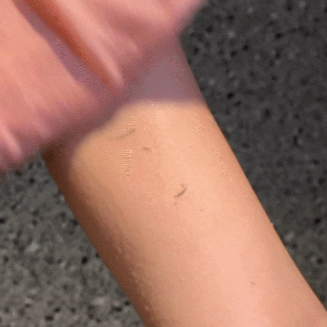 Pink CheekyGlo Exfoliating Glove being used to remove dead skin from arms.