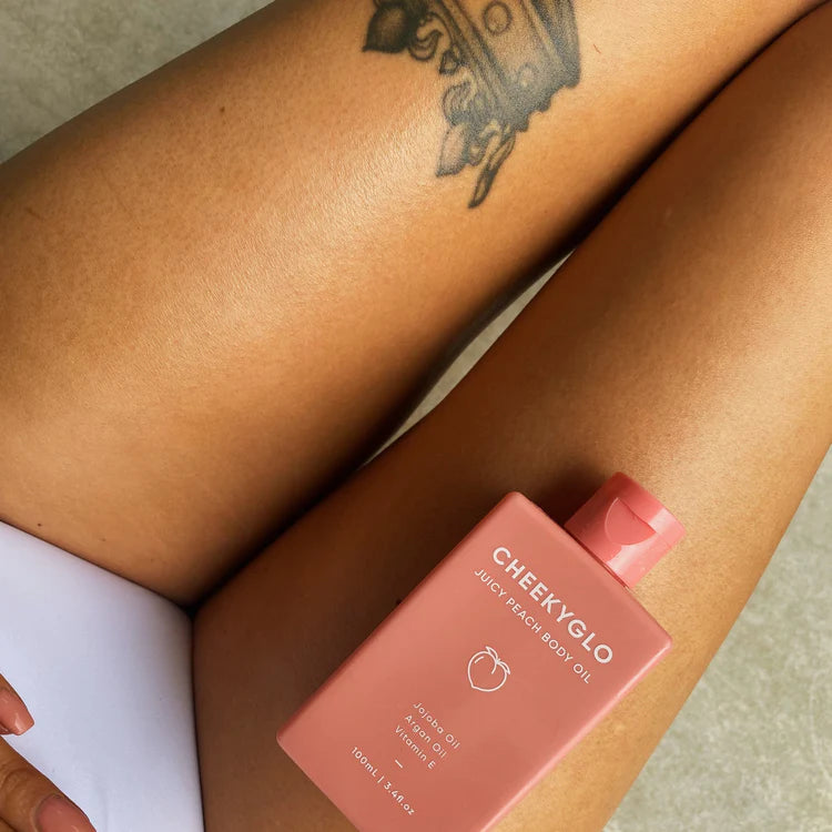 chekeyglo juicy peach body oil placed on legs