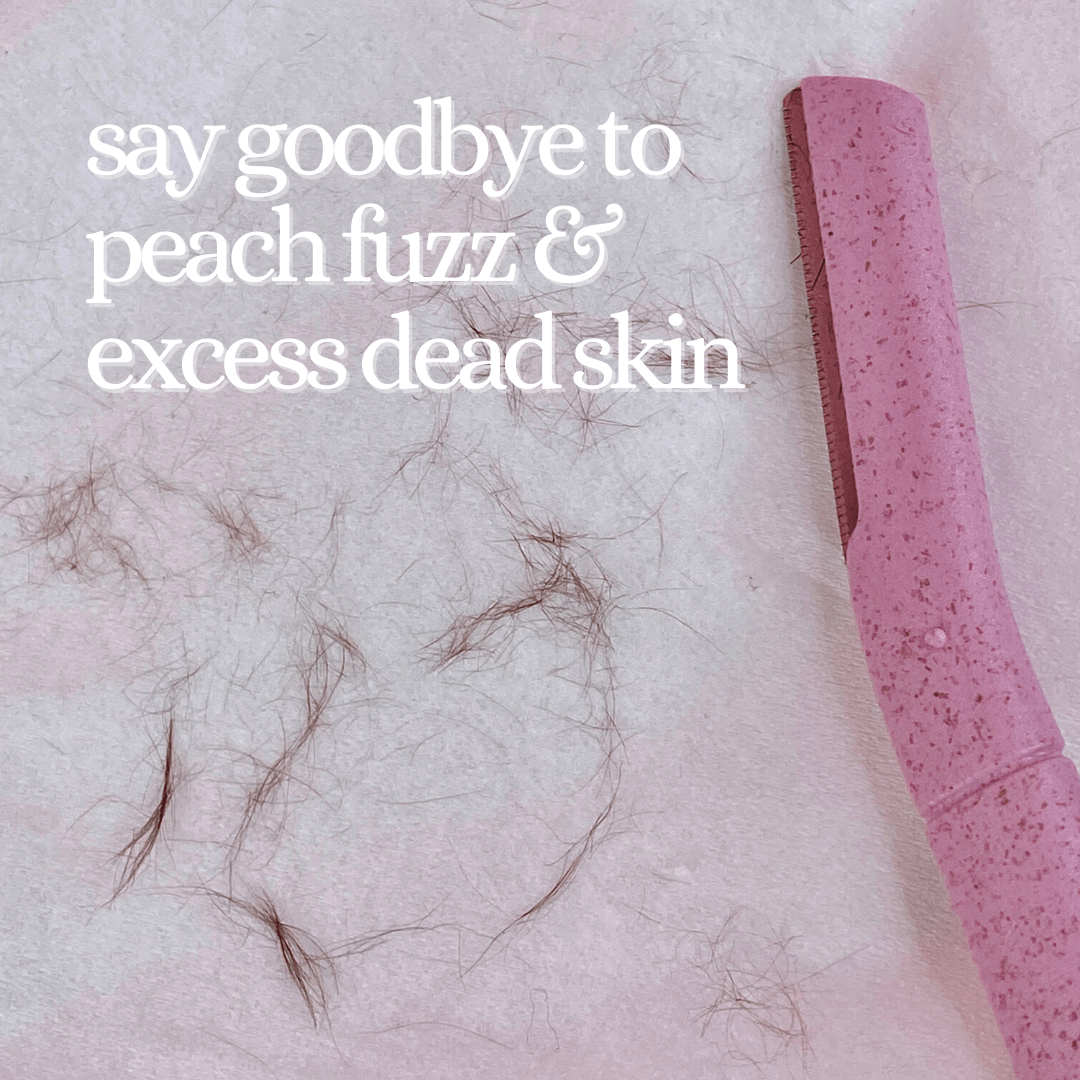 A pink CheekyGlo Dermablade facial razor is placed on a white surface with small, fine hair clippings scattered around. The text reads "say goodbye to peach fuzz & excess dead skin.