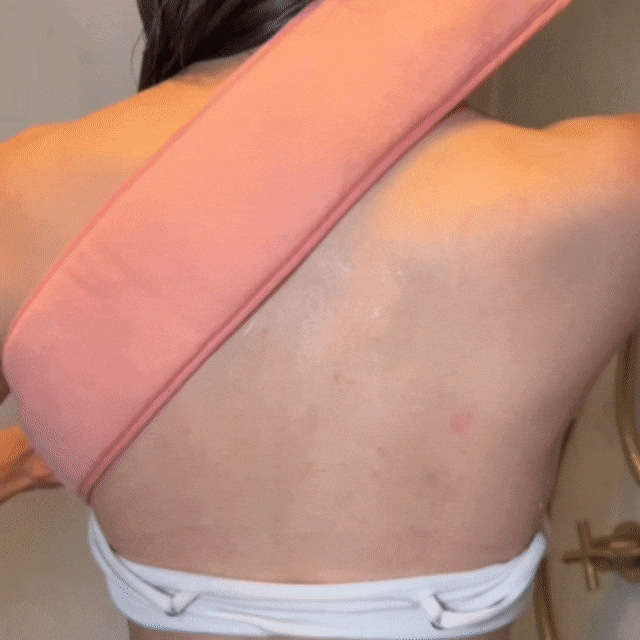 Woman scrubber her back with the CheekyGlo Back Scrubber in the Shower