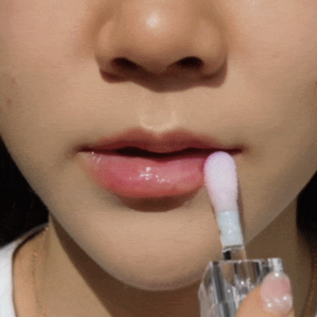 Woman applying the CheekyGlo Colour Changing Lip Oil in the shade Candy on her lips. 