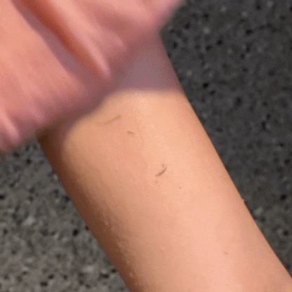 Pink CheekyGlo Exfoliating Glove being used to remove dead skin from arms.