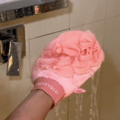 CheekyGlo Exfoliating Loofah Glove being rubbed over the skin to buff away dead skin, cleanse, and leave the body soft and smooth.