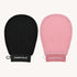 The image showcases the Black+Pink Exfoliating Glove Duo side by side against a plain background. One glove, designed for dead skin removal, is black with "CheekyGlo" printed in white letters, and the other glove is pink with the same branding. Each exfoliating mitt features a small loop for hanging, promising smoother skin.