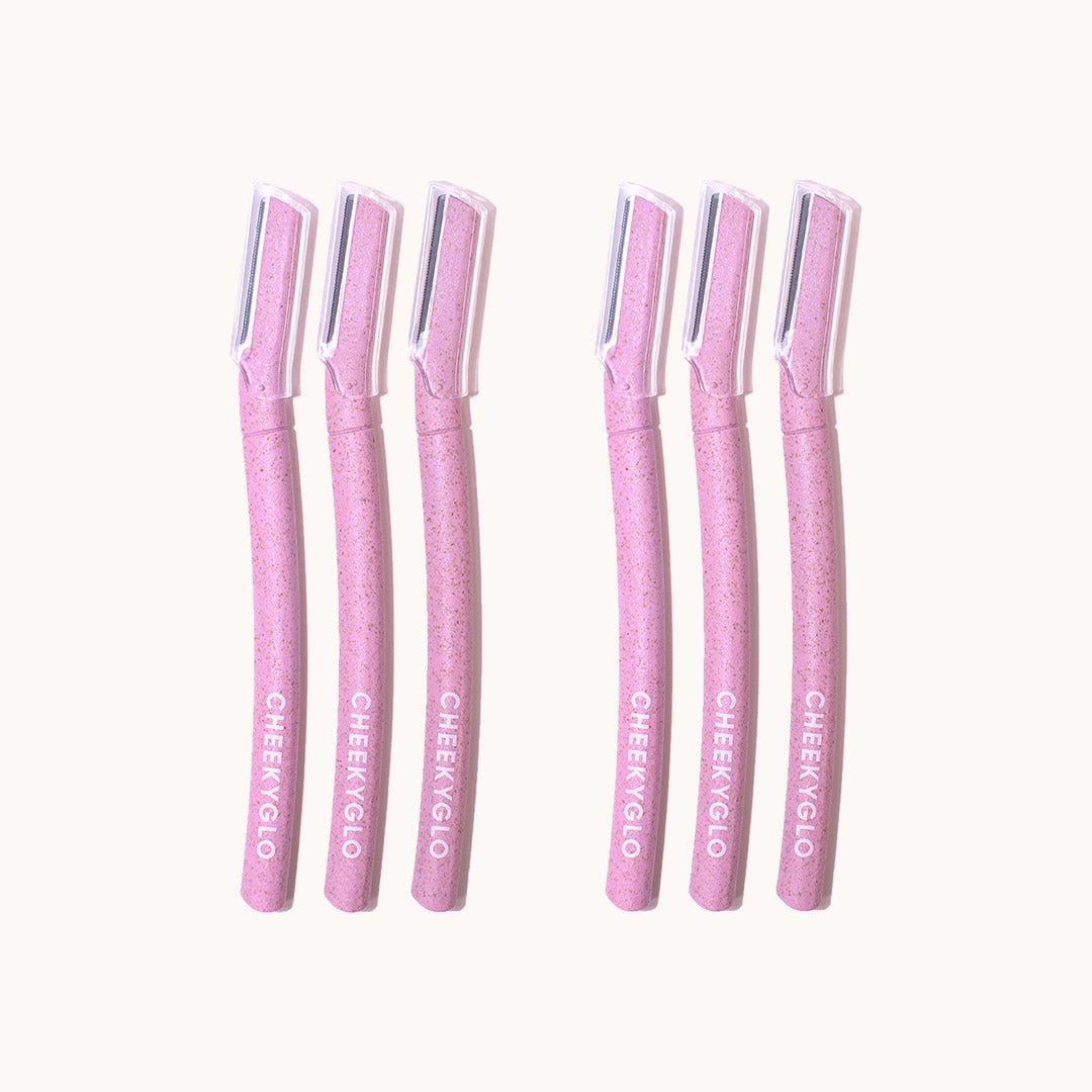 Six CheekyGlo Dermablades, each with a straight handle and a protective transparent cap covering the blade, are arranged in two rows of three. The handles are adorned with the brand name &quot;CheekyGlo&quot; printed in white, making them perfect for precise facial hair removal.