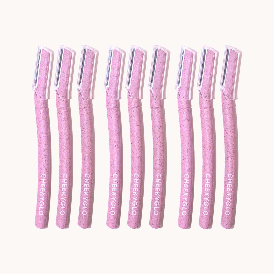 A row of nine CheekyGlo Dermablades facial razors, each featuring a sparkling handle and a protective cap, lined up against a light background. The brand name &quot;CheekyGlo&quot; is printed in white on each handle, highlighting their eco-friendly blades designed for efficient facial hair removal.