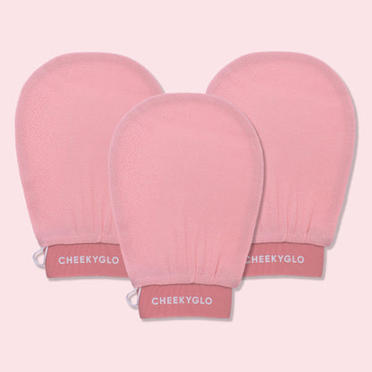 Three CheekyGlo Exfoliating Gloves are displayed against a light pink backdrop. The gloves are slightly rounded at the top with elasticated wristbands labeled &quot;CHEEKYGLO,&quot; promising smoother skin and a healthier glow.