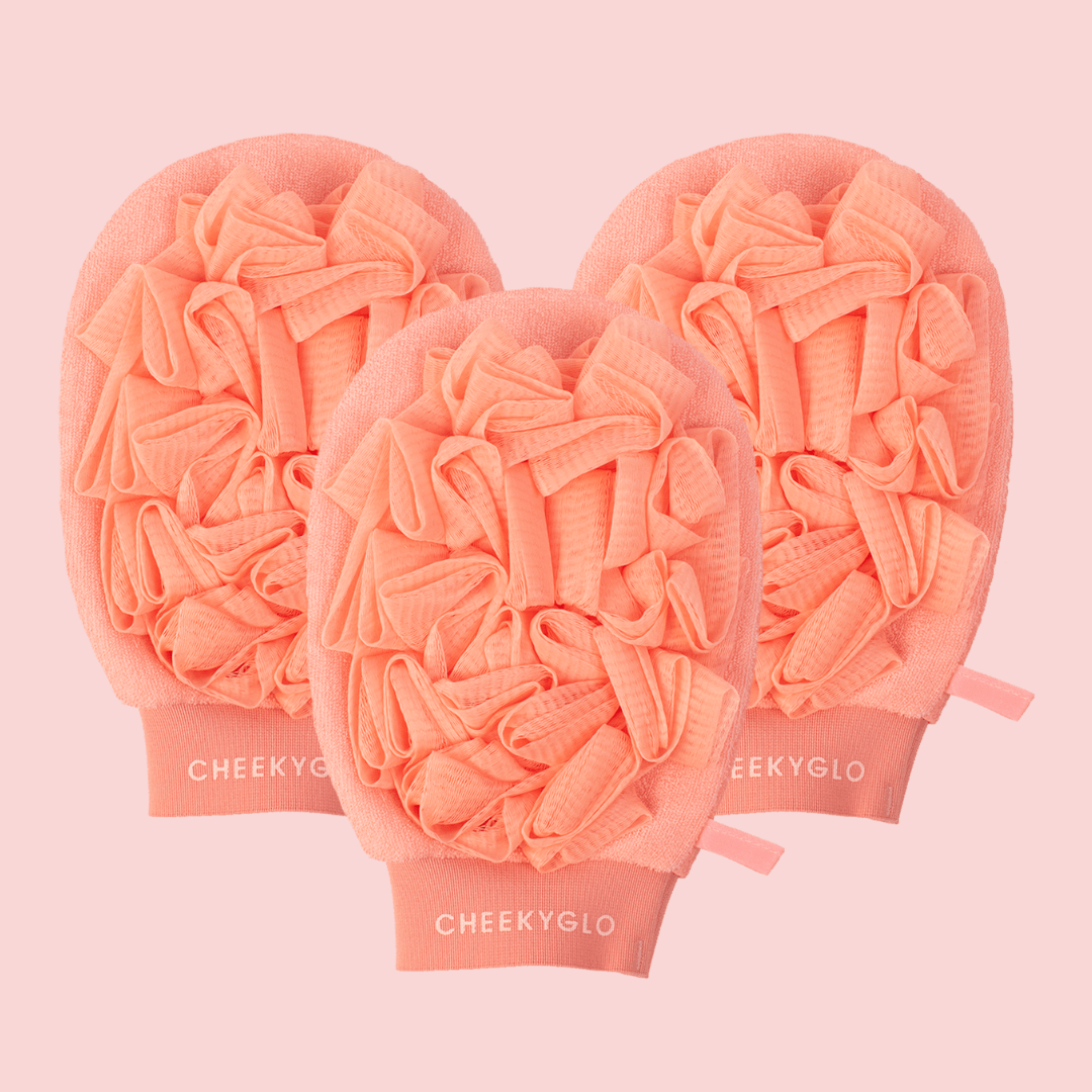 Three CheekyGlo Exfoliating Loofah Gloves with a ruffled texture are displayed against a light pink background. The words &quot;CHEEKYGLO&quot; are printed in white on the cuffs of each glove, making them perfect for skin smoothing and managing keratosis pilaris.