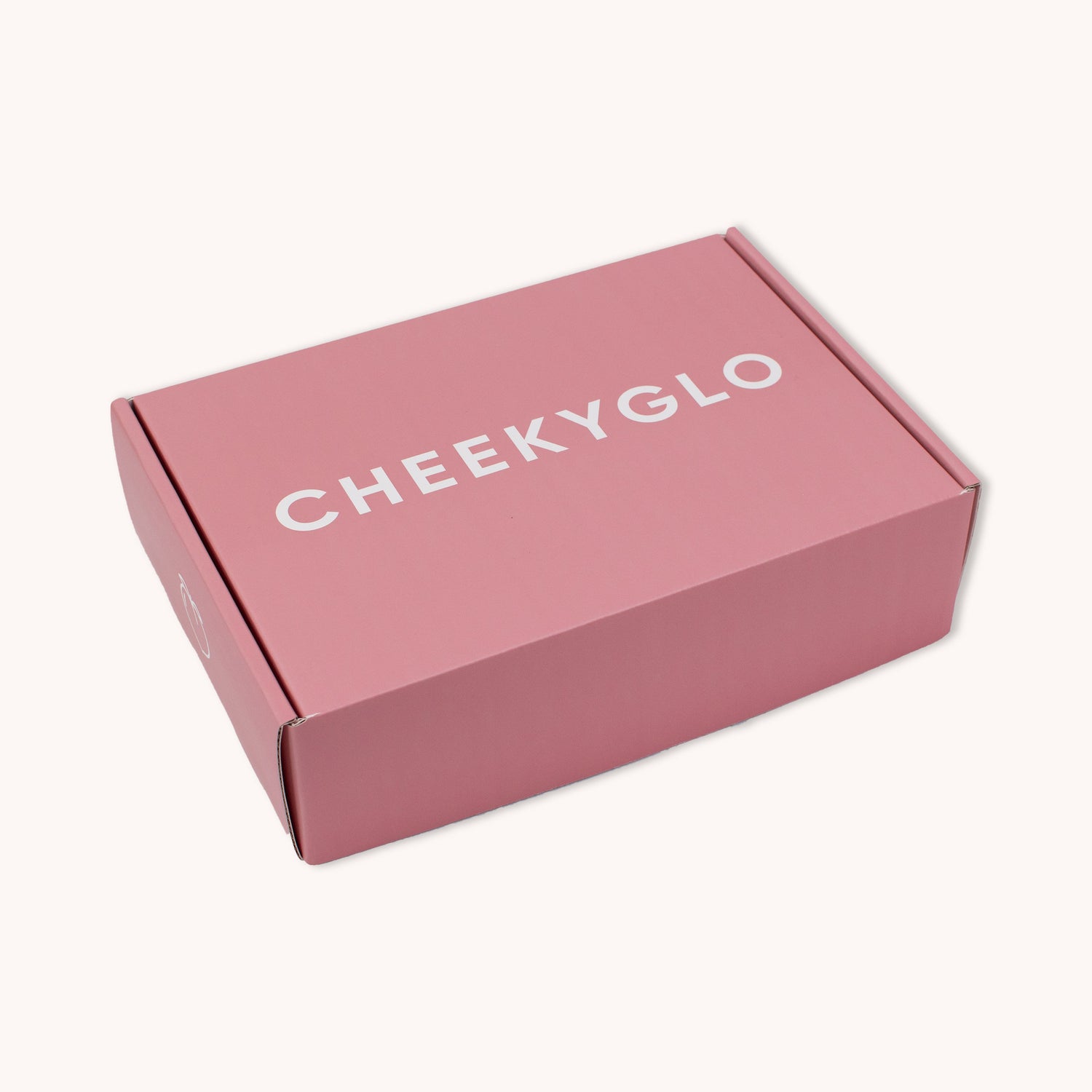 A neatly sealed, closed pink cardboard box with the brand name &quot;CheekyGlo&quot; printed in large white letters on the top surface. This CheekyGlo Premium Gift Box is set against a plain, light-colored background and is perfect for holding precious self-care products or including a special note for someone dear.