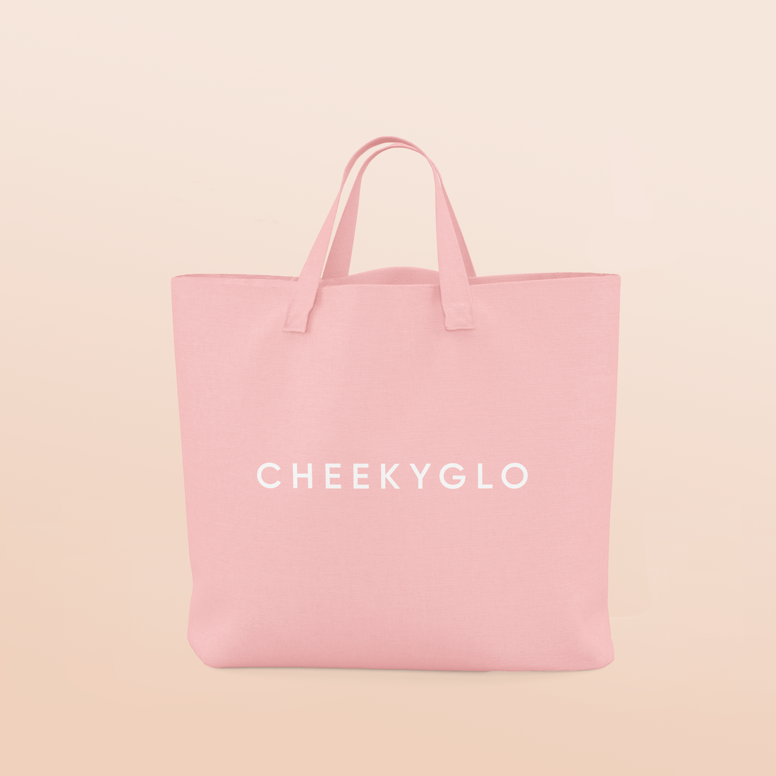 A light peach CheekyGlo Tote Bag with the brand name &quot;CHEEKYGLO&quot; printed in bold white capital letters across the center. This pink tote bag has sturdy reinforced handles at the top, making it ideal for carrying groceries while maintaining a soft and clean appearance.