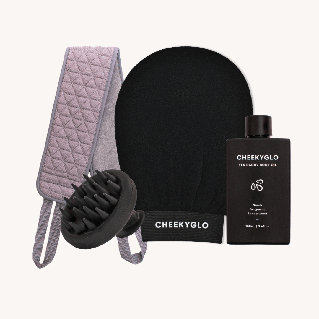 The Everyday Essentials Set by CheekyGlo includes an Exfoliating Body Glove, a scalp scrubber massage brush, a quilted grey back strap with an Exfoliating Back Scrubber feature, and a bottle of &quot;Yes Daddy Body Oil.